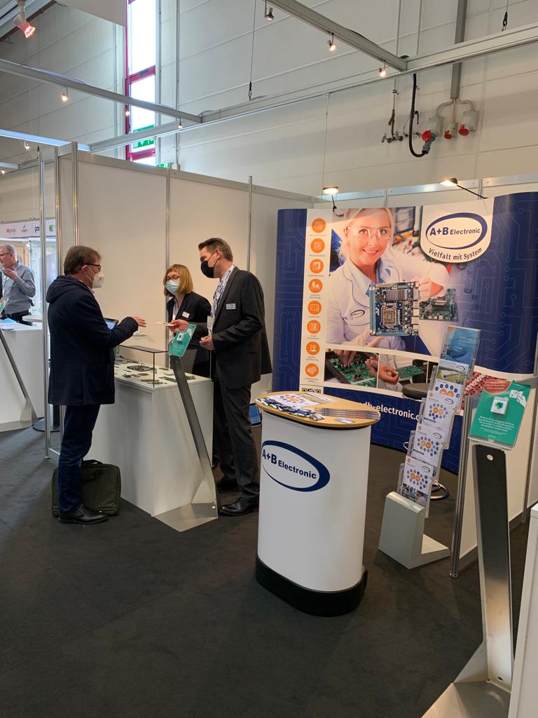 Mitarbeiter beraten eine Person auf einer Messe